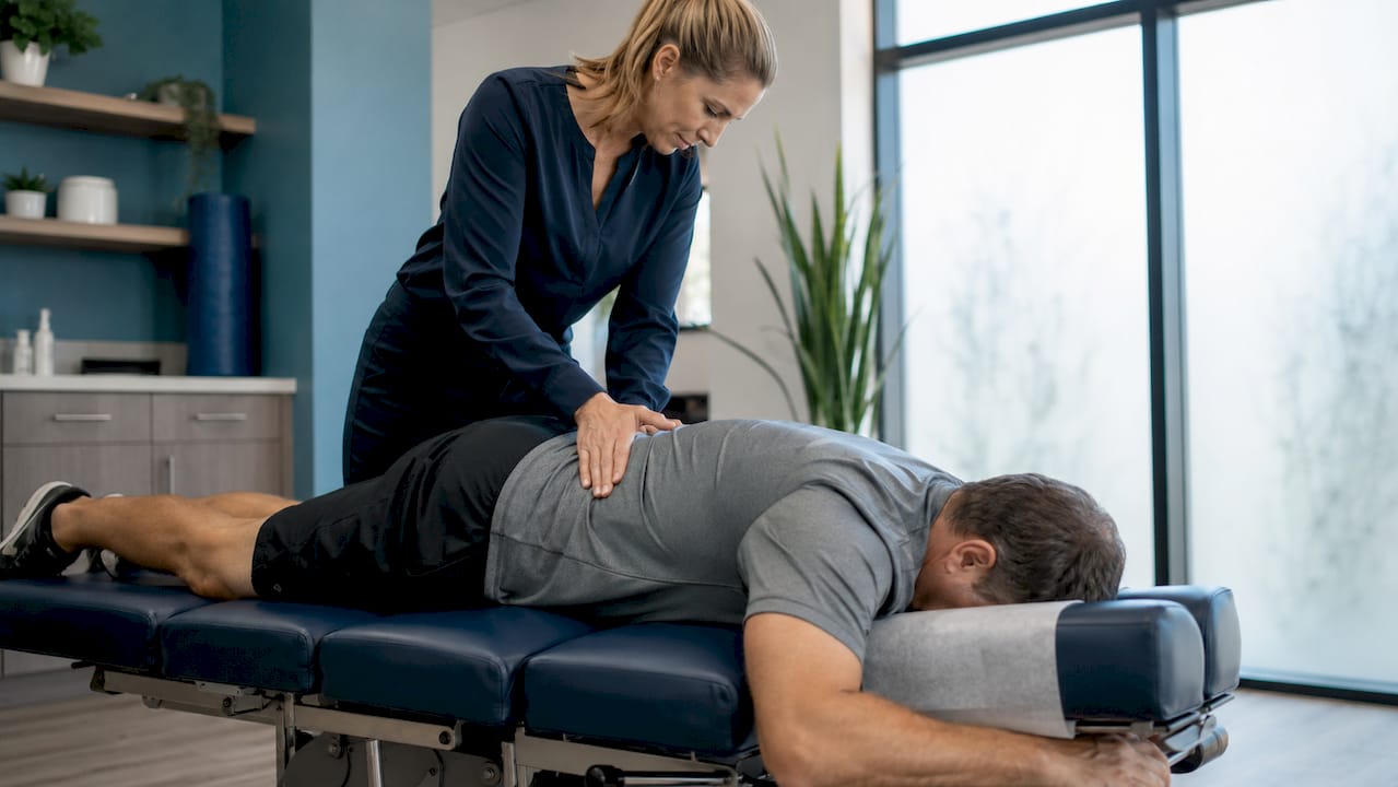 Chiropractor adjusting patient’s lower back in clinic