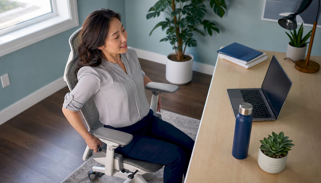 Woman adjusting ergonomic chair at office desk