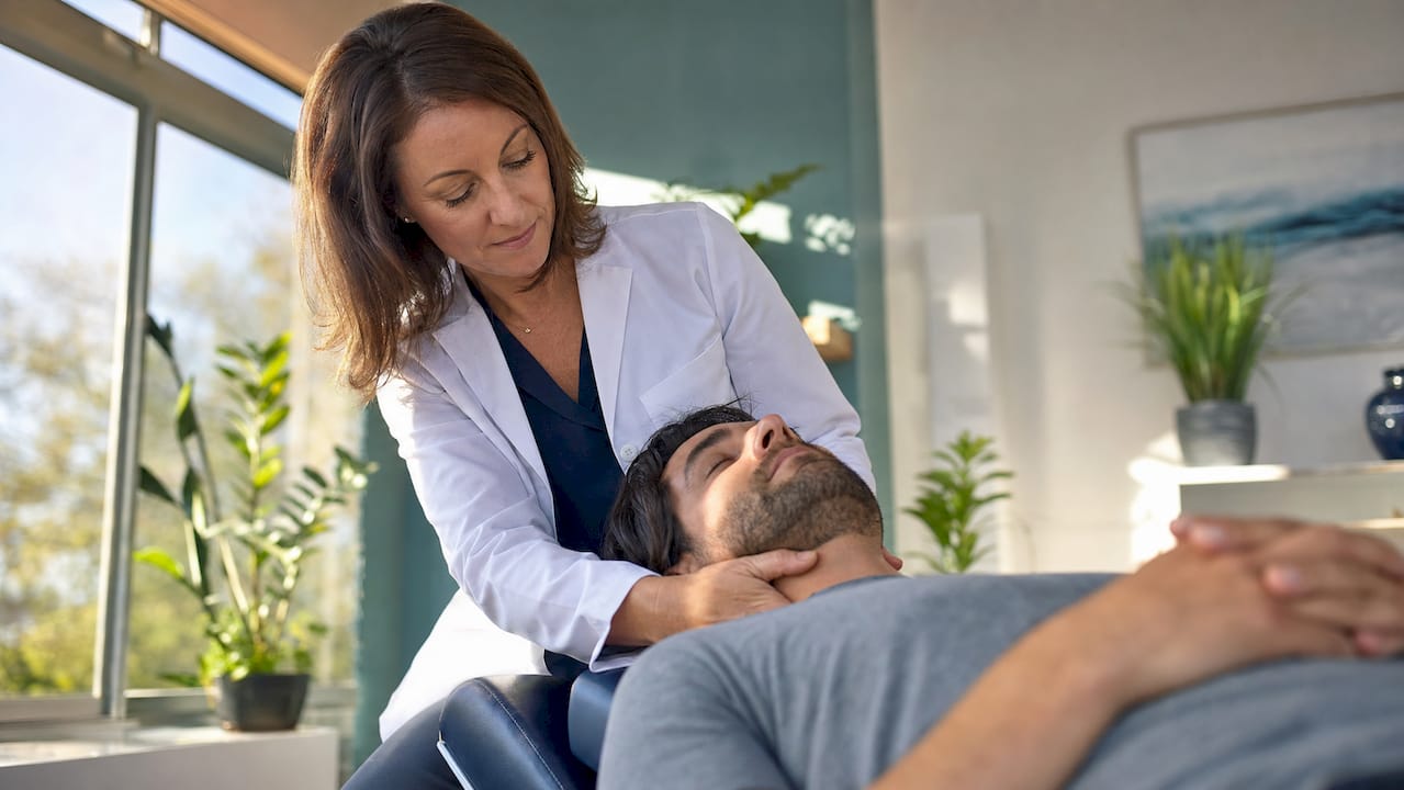 Chiropractor adjusting patient’s neck in clinic