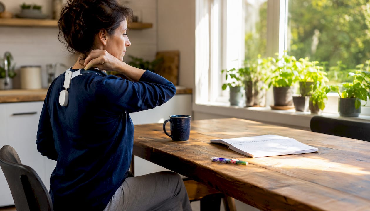 Woman adjusting posture wearable in home office
