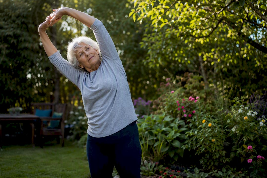 Senior gently stretching arms at home