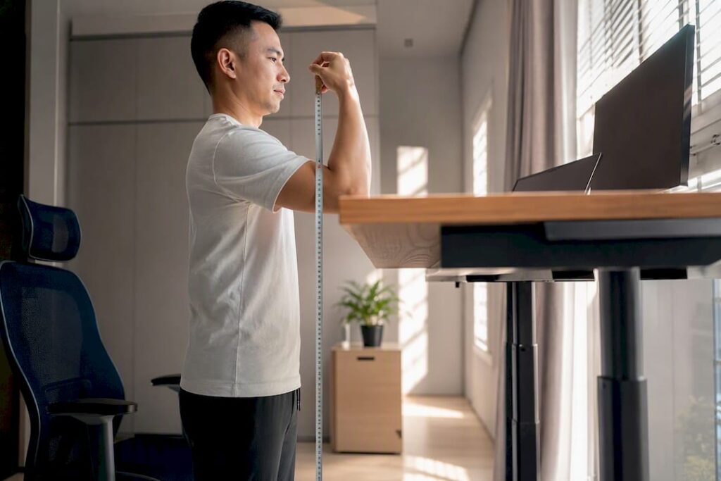 Worker measuring elbow height beside standing desk